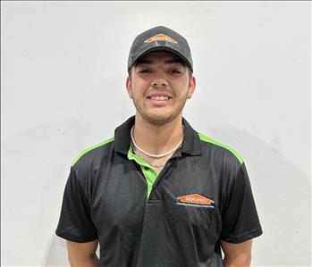 Male employee wearing a black SERVPRO® shirt, grey hat and white necklace 