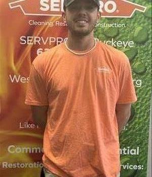 Male employee wearing a orange SERVPRO® shirt, grey hat and white necklace 
